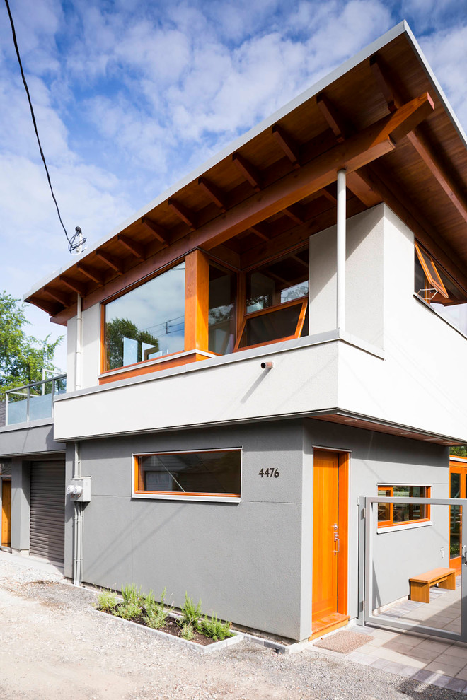 Small trendy gray two-story stucco exterior home photo in Vancouver with a shed roof