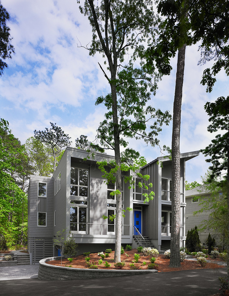 Esempio della facciata di una casa grande grigia contemporanea a due piani con rivestimento con lastre in cemento e copertura in metallo o lamiera