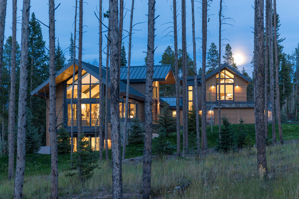 Cette photo montre une grande façade de maison marron tendance en bois à deux étages et plus avec un toit à deux pans et un toit en métal.
