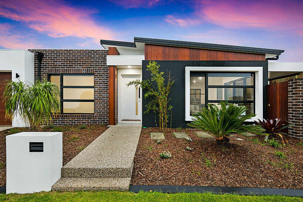 Example of a trendy one-story brick exterior home design in Brisbane with a metal roof