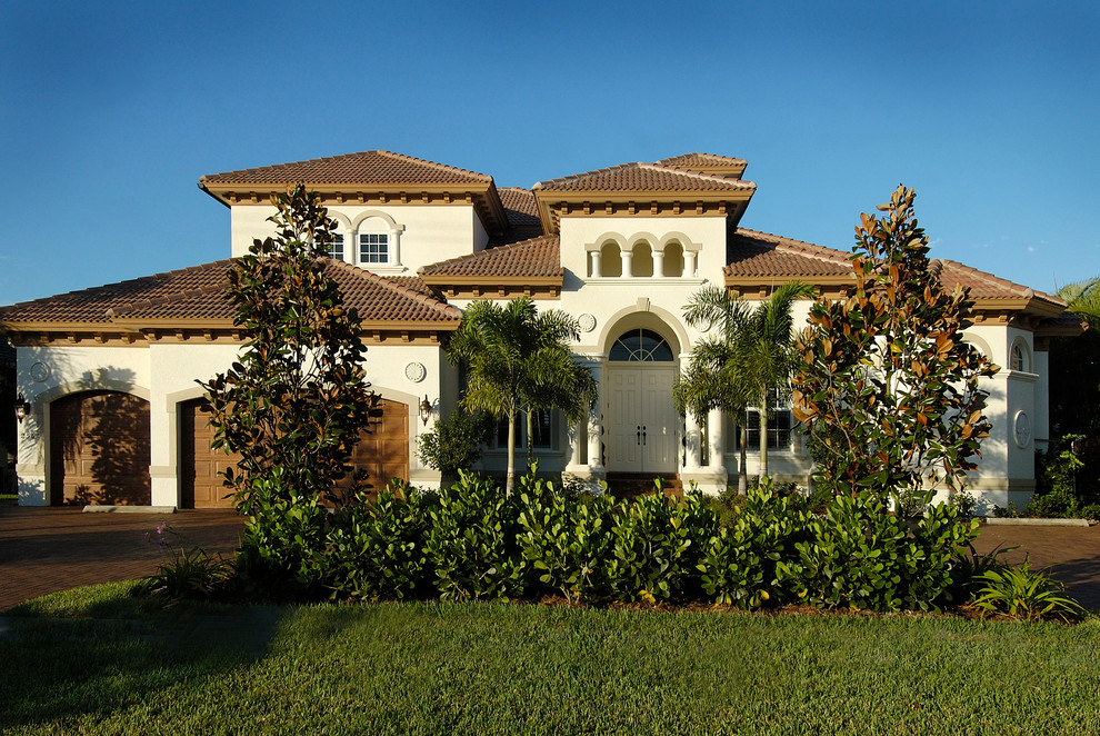 Tuscan beige two-story stucco house exterior photo in Miami with a shingle roof