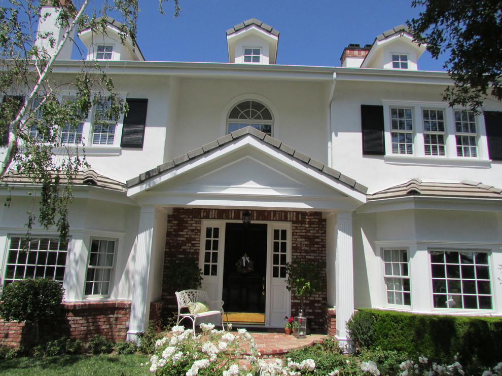 Mittelgroßes, Zweistöckiges Klassisches Haus mit Putzfassade, weißer Fassadenfarbe und Satteldach in Los Angeles