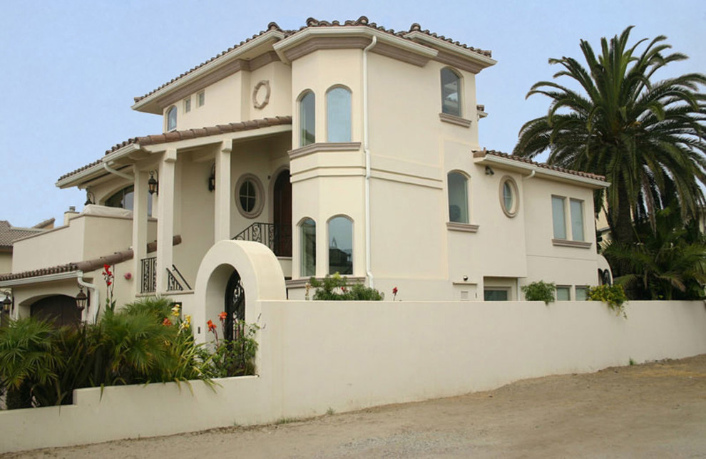 Источник вдохновения для домашнего уюта: трехэтажный, бежевый дом среднего размера в средиземноморском стиле с облицовкой из цементной штукатурки и двускатной крышей