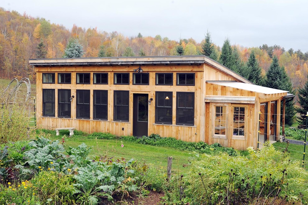 Aménagement d'une petite façade de maison montagne en bois de plain-pied avec un toit en appentis.