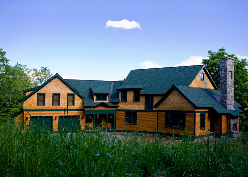 Ejemplo de fachada marrón clásica grande de dos plantas con revestimiento de madera y tejado a dos aguas