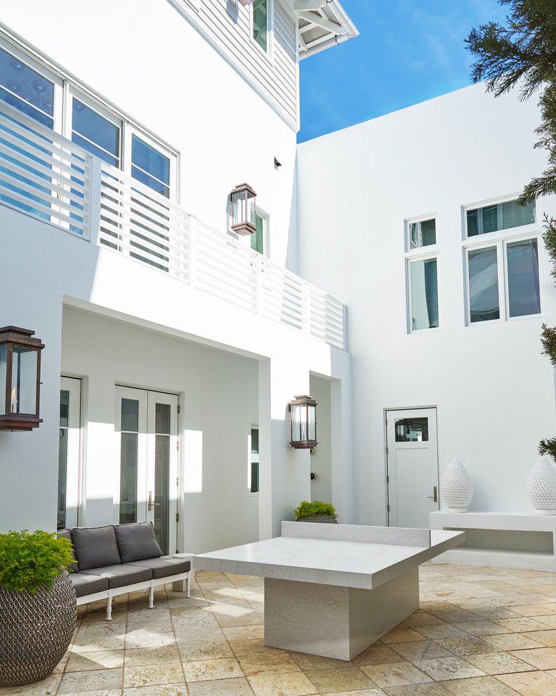 Пример оригинального дизайна: большой, трехэтажный, белый частный загородный дом в морском стиле с облицовкой из цементной штукатурки