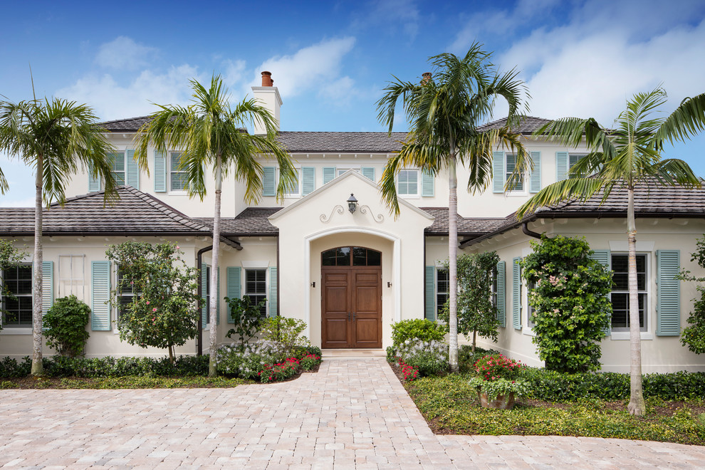 Example of a beach style beige two-story house exterior design in Miami with a hip roof