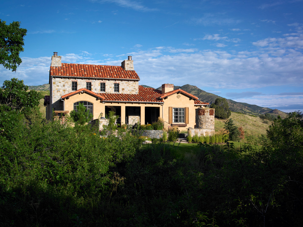 Cette photo montre une grande façade de maison beige méditerranéenne de plain-pied avec un revêtement mixte et un toit à quatre pans.