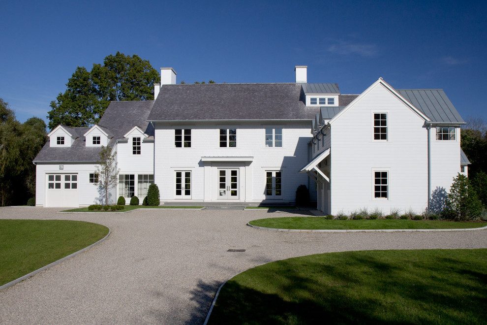 Cette image montre une grande façade de maison blanche rustique à un étage avec un revêtement en vinyle et un toit à deux pans.