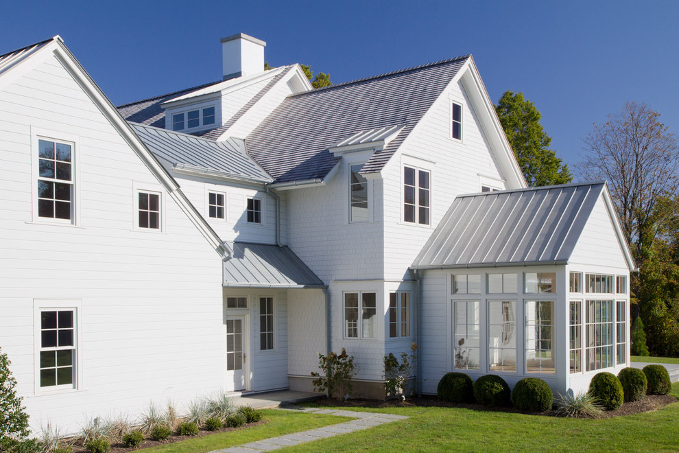 Idée de décoration pour une grande façade de maison blanche champêtre à un étage avec un toit mixte, un revêtement en vinyle et un toit à deux pans.