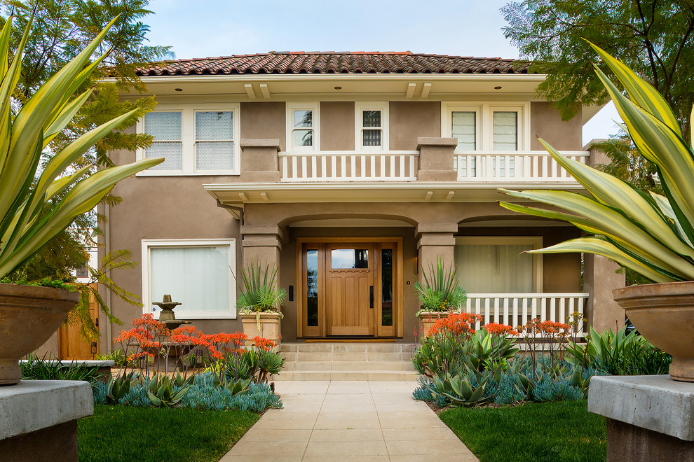 Mid-sized elegant brown two-story stucco exterior home photo in Los Angeles with a hip roof