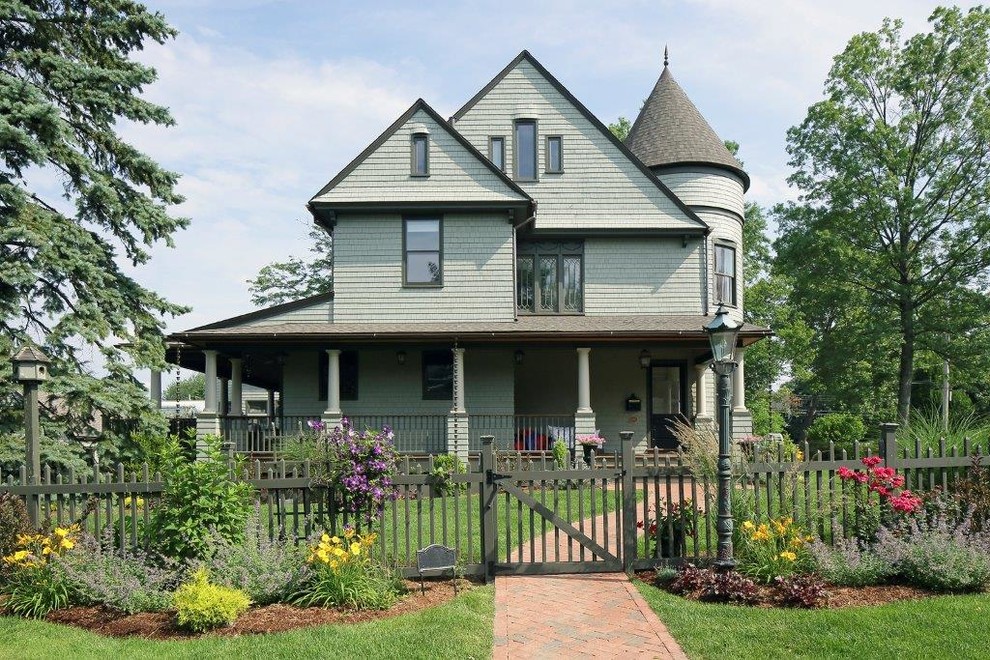На фото: трехэтажный, деревянный, зеленый частный загородный дом в викторианском стиле с двускатной крышей