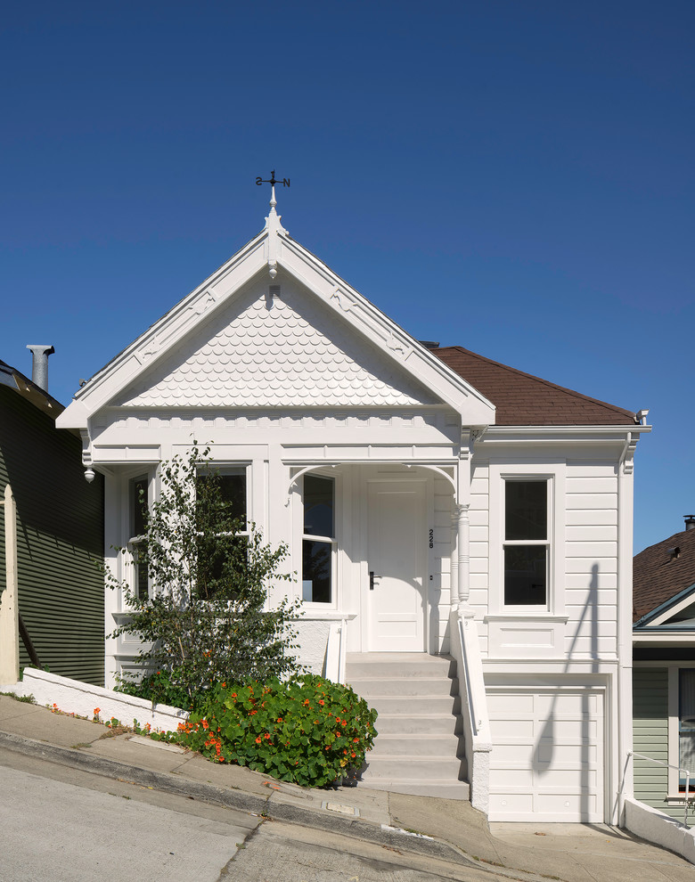 Idee per la facciata di una casa bianca vittoriana a due piani con rivestimento in legno, tetto a capanna e terreno in pendenza