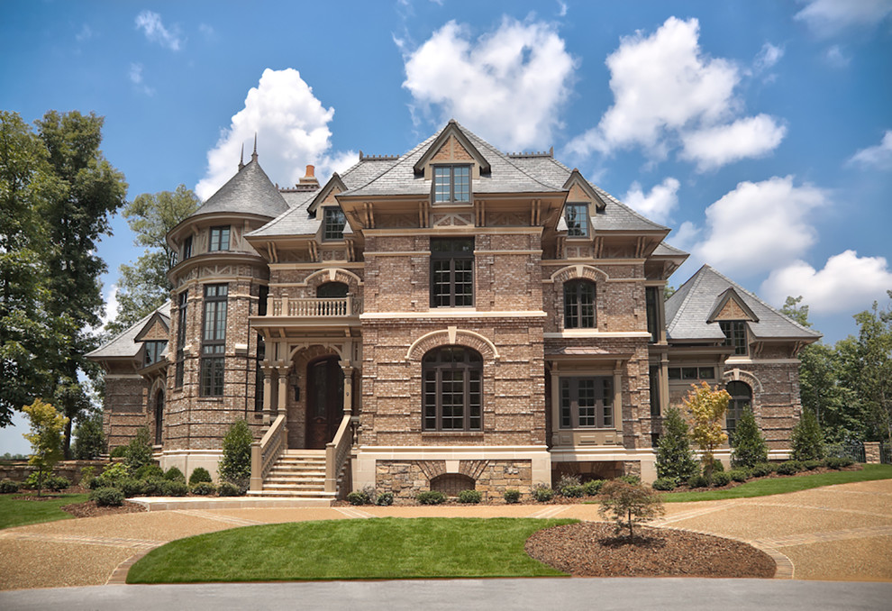 Inspiration for a huge victorian beige three-story brick exterior home remodel in Other with a clipped gable roof