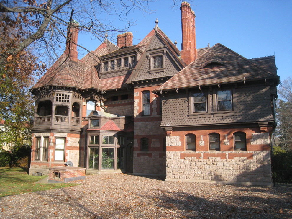 Ejemplo de fachada marrón clásica grande de tres plantas con revestimientos combinados y tejado a cuatro aguas