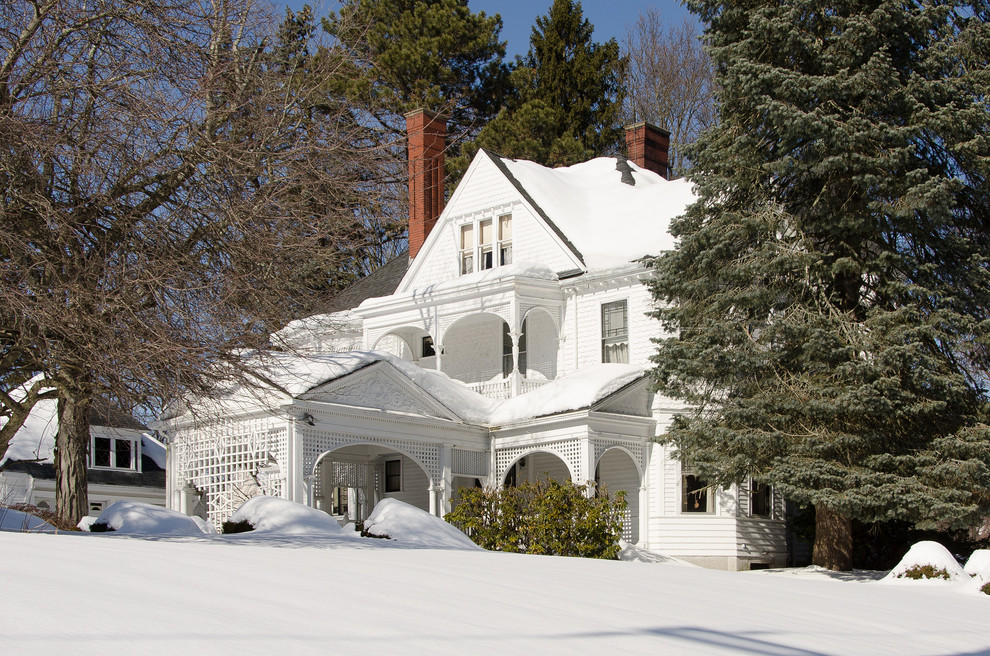 На фото: большой, трехэтажный, деревянный, белый дом в викторианском стиле с двускатной крышей с