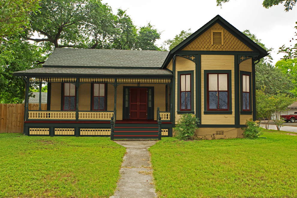Cette photo montre une petite façade de maison jaune victorienne en bois de plain-pied.