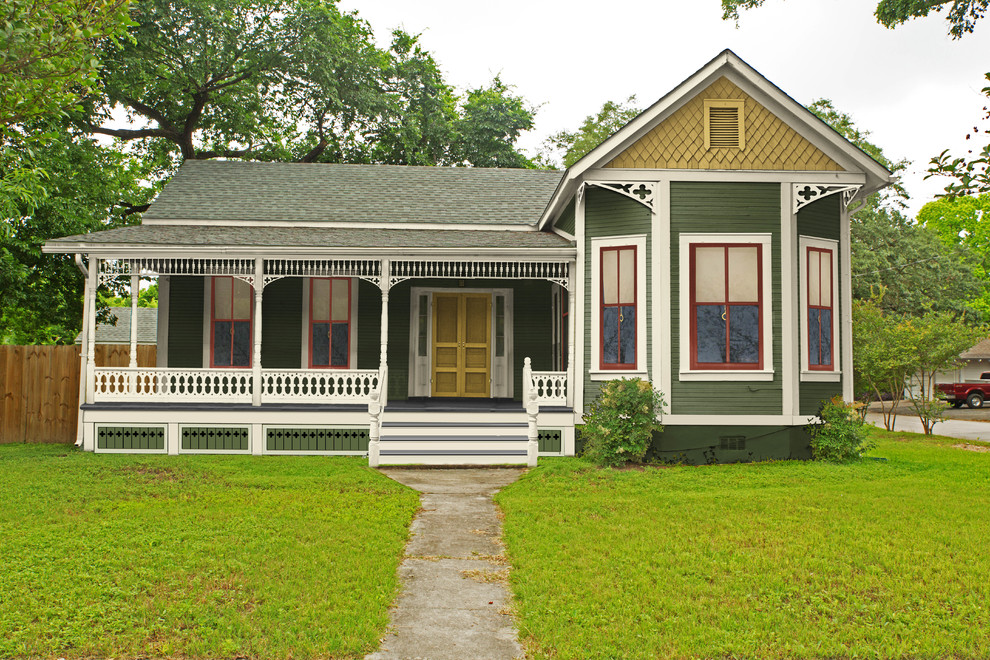 Foto della facciata di una casa piccola verde vittoriana a un piano con rivestimento in legno e abbinamento di colori