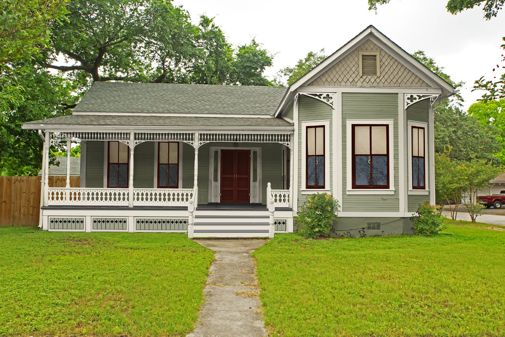 Small and green victorian bungalow house exterior in Atlanta with wood cladding.