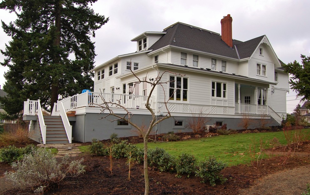 Imagen de fachada blanca clásica de tamaño medio de dos plantas con revestimiento de madera y tejado a dos aguas