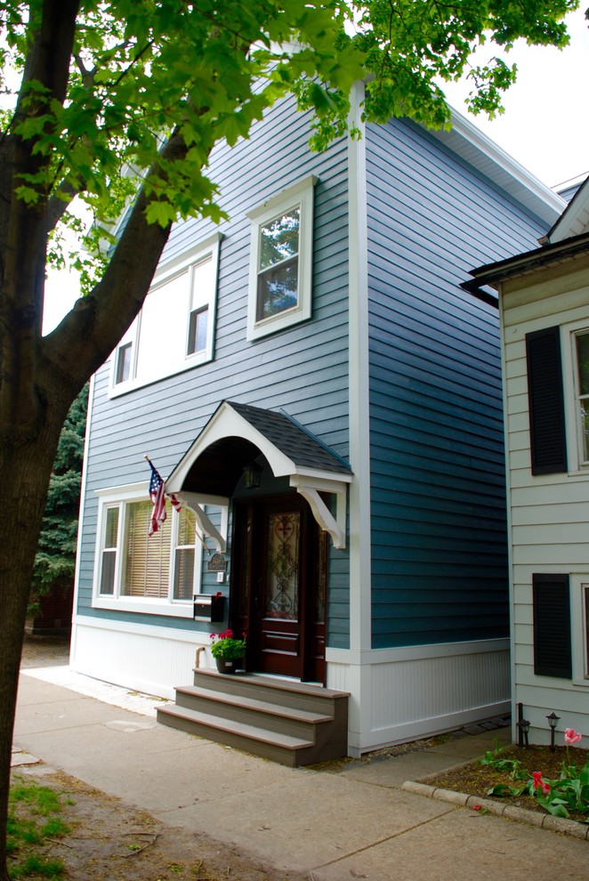 Medium sized and blue victorian detached house in Chicago with concrete fibreboard cladding, three floors, a pitched roof and a shingle roof.