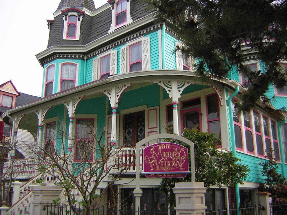 На фото: большой, трехэтажный, деревянный, зеленый дом в викторианском стиле с