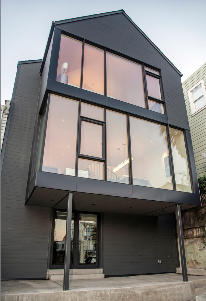 Imagen de fachada de casa gris moderna de tamaño medio de tres plantas con revestimiento de madera y tejado a dos aguas