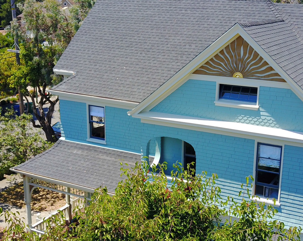 Foto de fachada de casa azul clásica de dos plantas con revestimiento de madera, tejado a dos aguas y tejado de teja de madera