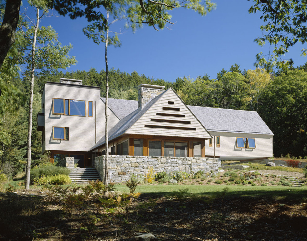 Esempio della facciata di una casa beige contemporanea a tre piani con tetto a capanna e rivestimento in legno