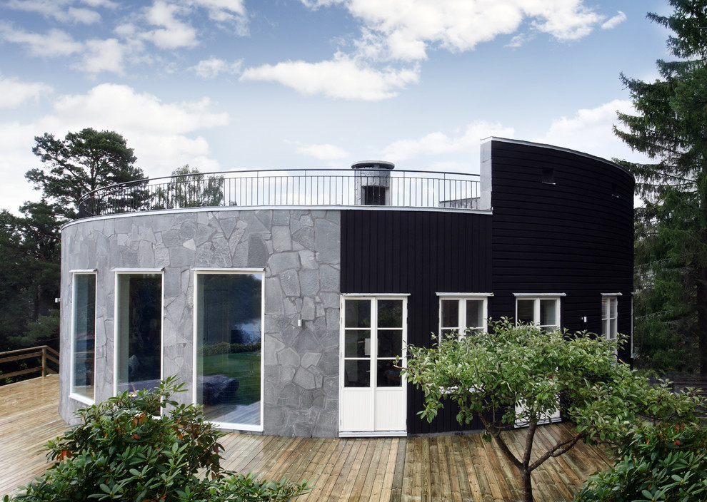 Réalisation d'une grande façade de maison grise nordique en pierre de plain-pied avec un toit plat.