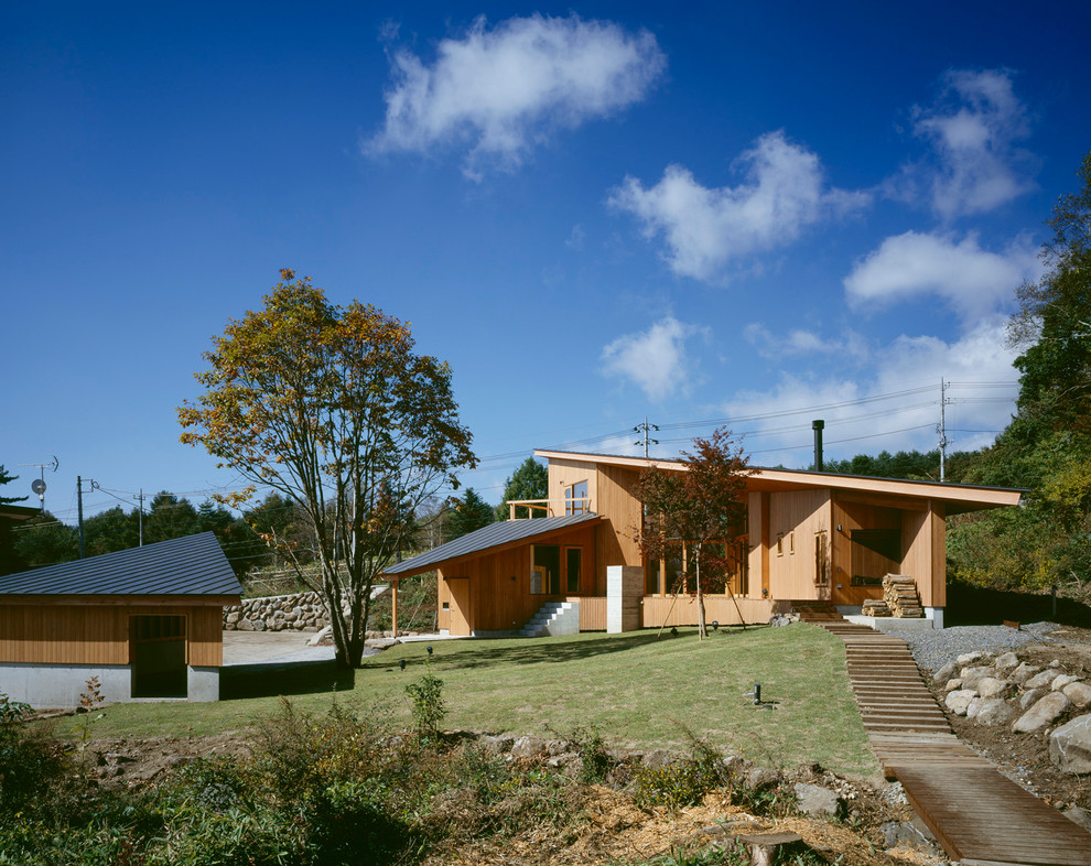 Foto della facciata di una casa marrone moderna a due piani di medie dimensioni con rivestimento in legno e copertura in metallo o lamiera