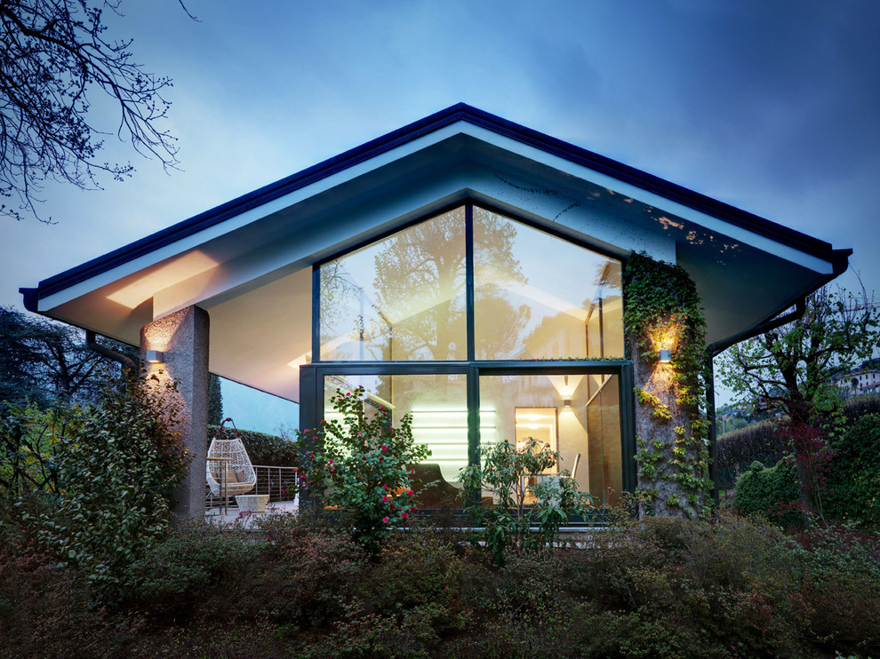 На фото: одноэтажный, стеклянный дом в современном стиле с двускатной крышей с