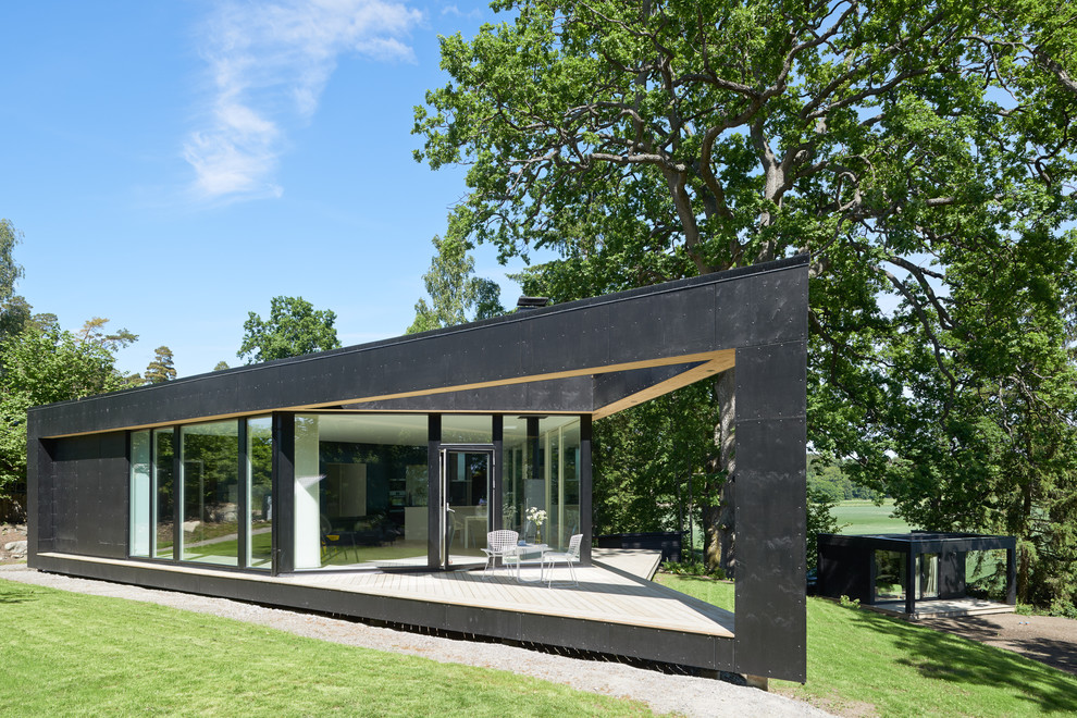 This is an example of a black scandinavian bungalow glass house exterior in Stockholm with a flat roof.