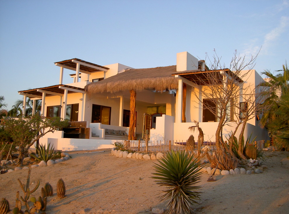 Foto de fachada blanca tropical de tamaño medio de dos plantas con revestimiento de estuco y tejado plano