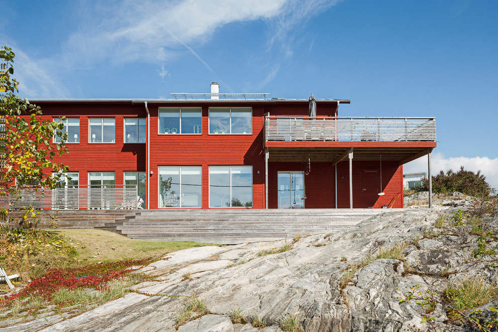 Ispirazione per la facciata di una casa grande rossa scandinava a due piani con rivestimento in legno