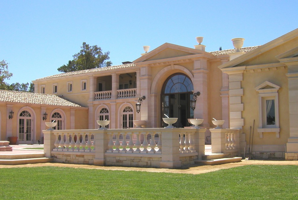 Стильный дизайн: большой, двухэтажный, желтый дом в средиземноморском стиле с облицовкой из цементной штукатурки и двускатной крышей - последний тренд