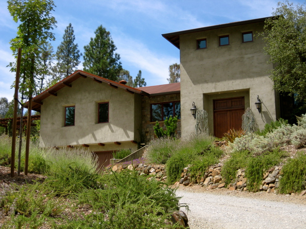 Diseño de fachada de casa marrón mediterránea grande de dos plantas con revestimiento de estuco y tejado a cuatro aguas
