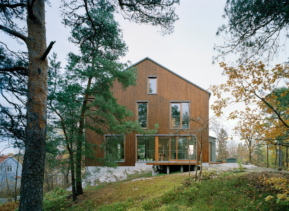 Foto della facciata di una casa ampia marrone scandinava a tre piani con rivestimento in legno e tetto a capanna