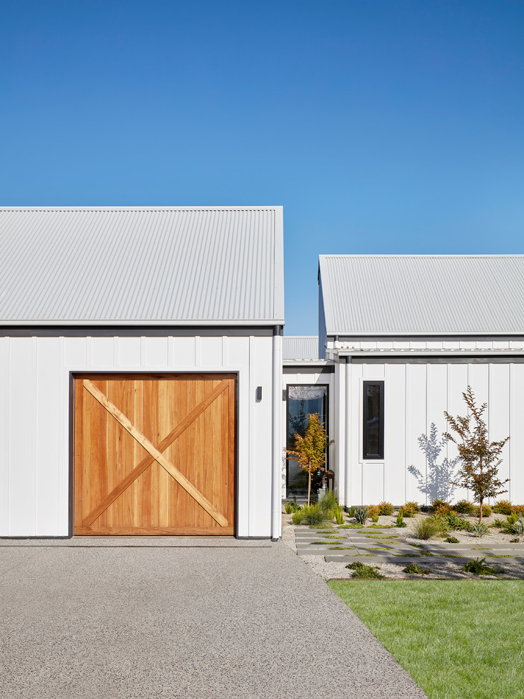 Idées déco pour une façade de maison blanche campagne en béton de taille moyenne et à un étage avec un toit à deux pans et un toit en métal.