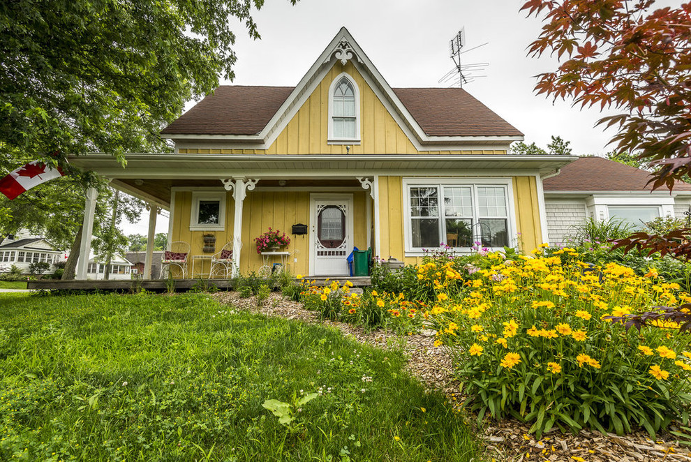 Small and yellow victorian bungalow detached house in Toronto with wood cladding.