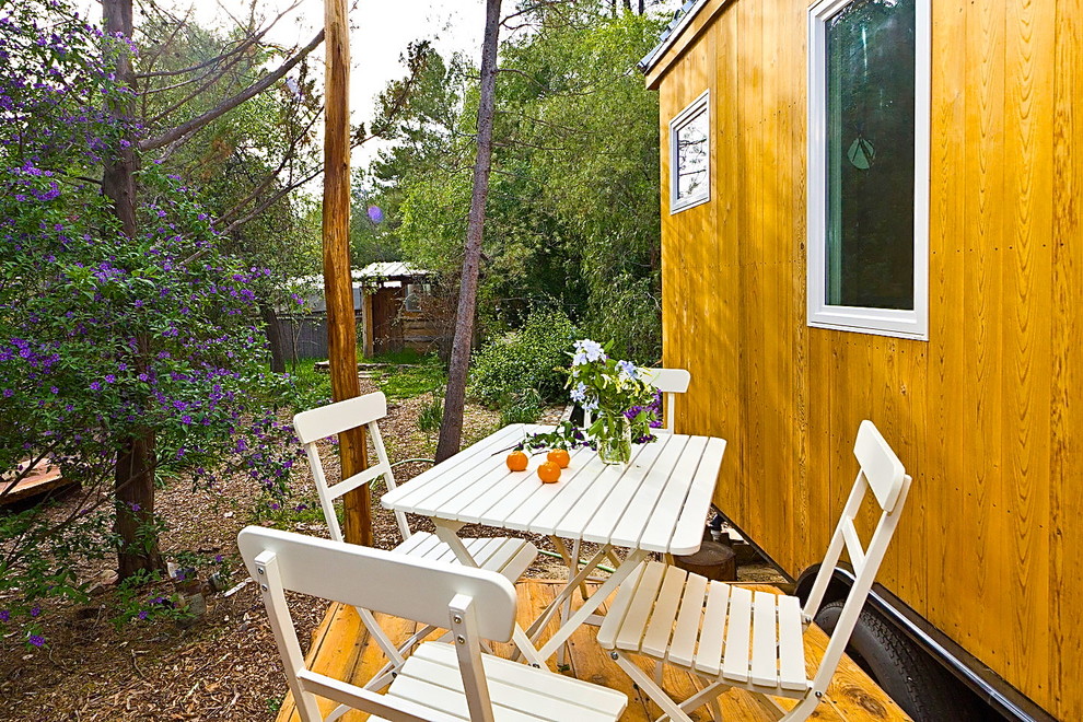На фото: маленький, деревянный, коричневый дом в современном стиле с разными уровнями и двускатной крышей для на участке и в саду с