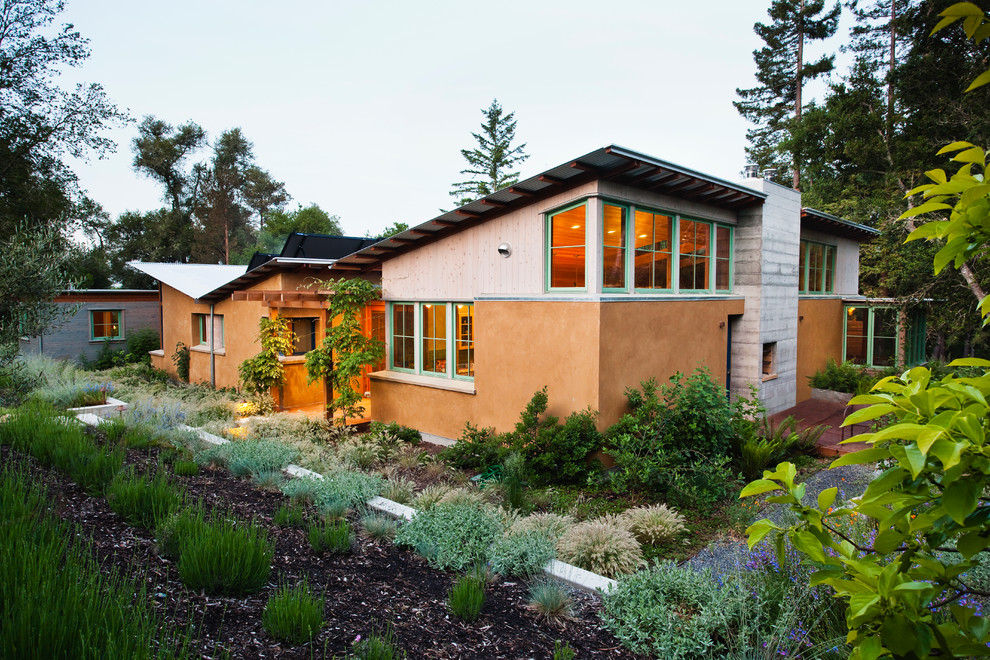 Aménagement d'une grande façade de maison beige contemporaine en stuc de plain-pied avec un toit en appentis.