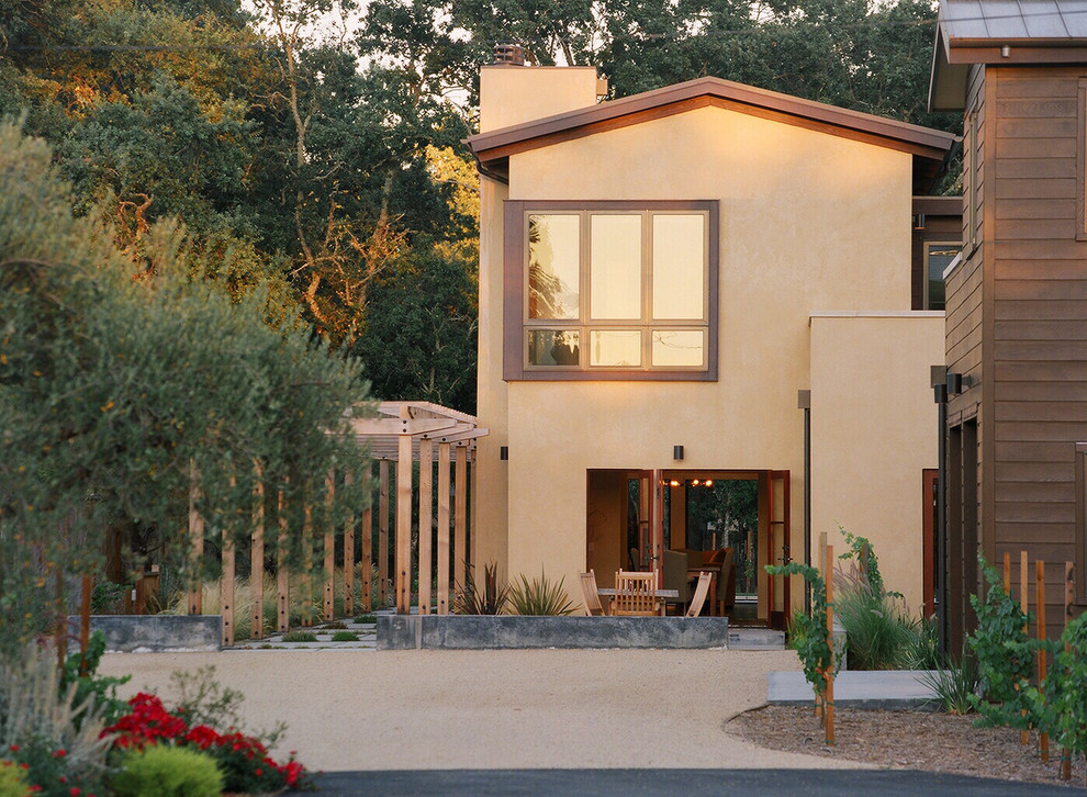 Réalisation d'une façade de maison beige design en stuc de taille moyenne et à un étage avec un toit à deux pans.