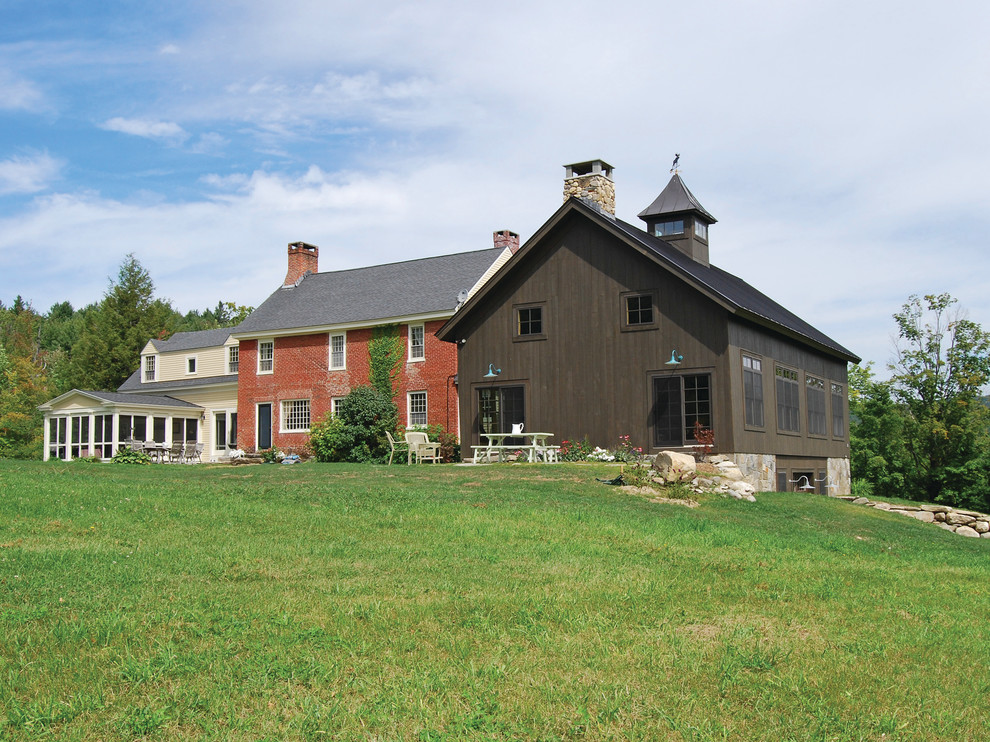 Immagine della facciata di una casa country a tre piani con rivestimento in legno