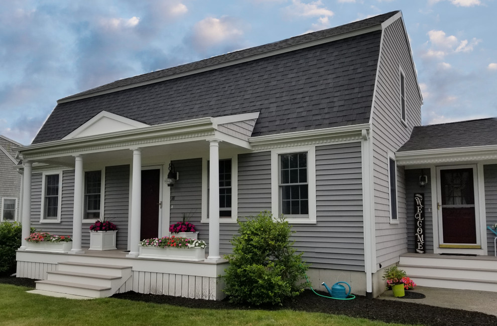 Cette photo montre une façade de maison grise de taille moyenne avec un revêtement en vinyle, un toit de Gambrel et un toit en shingle.