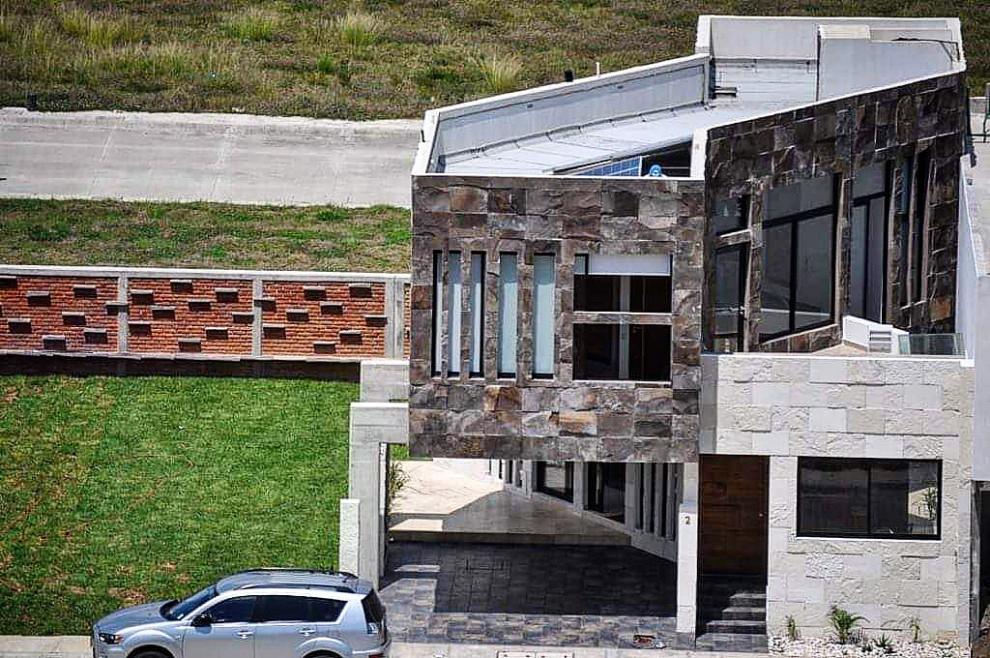 Cette image montre une façade de maison multicolore design en pierre de taille moyenne et à un étage avec un toit plat et un toit mixte.