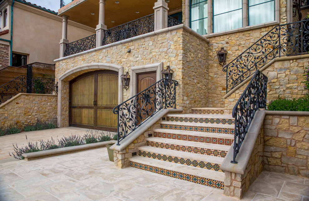 This is an example of a beige mediterranean house exterior in San Diego with three floors and stone cladding.