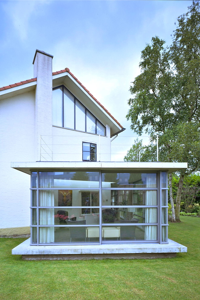 Aménagement d'une grande façade de maison grise moderne en verre de plain-pied.
