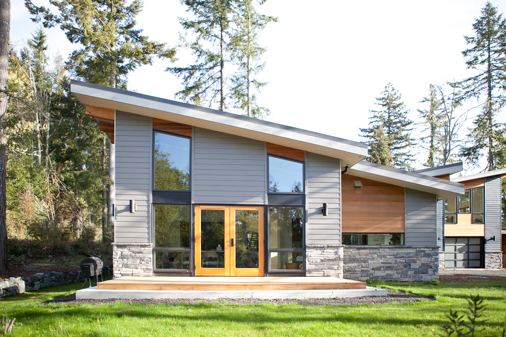Aménagement d'une façade de maison grise contemporaine en bois à un étage avec un toit en appentis.