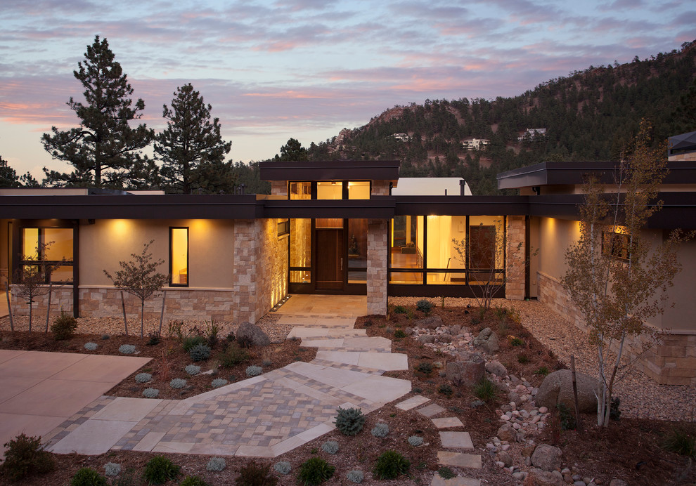 Design ideas for a large and beige contemporary two floor house exterior in Denver with stone cladding and a flat roof.